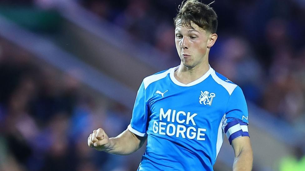 Harry Leonard in action for Peterborough wearing a blue playing shirt